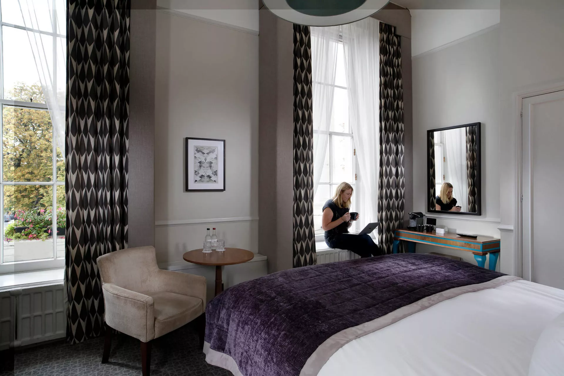 Queens Hotel Deluxe bedroom with person drinking coffee